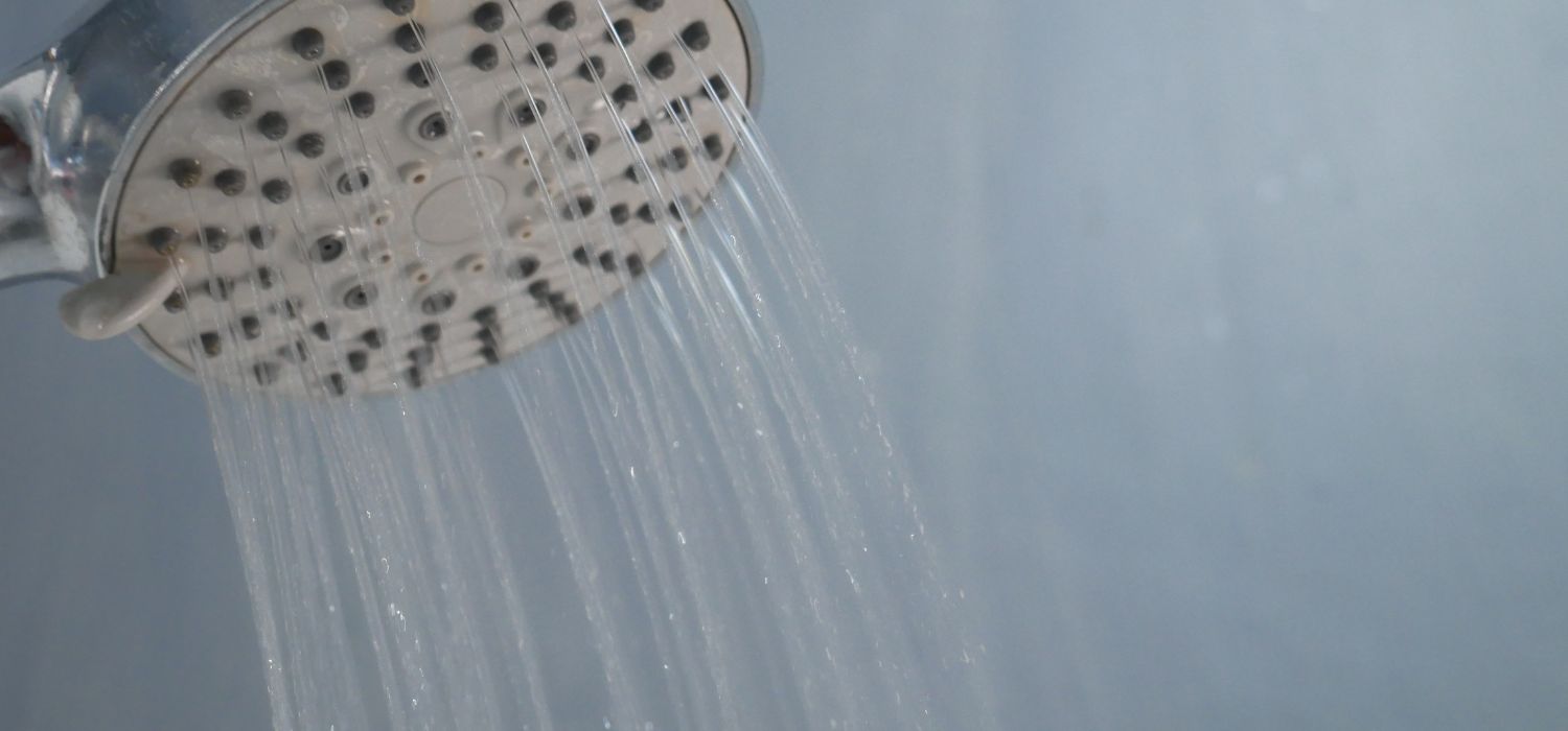 Water flows weakly from a showerhead, illustrating low well water pressure that affects everyday household use.